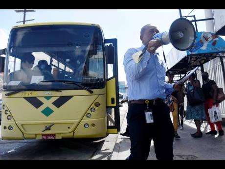Keith Blake, general manager of the Half-Way Transport Centre, uses a megaphone to notify stranded commuters of extra buses that would be traversing St Andrew West Rural routes which have been hit by bus strikes  for two days.