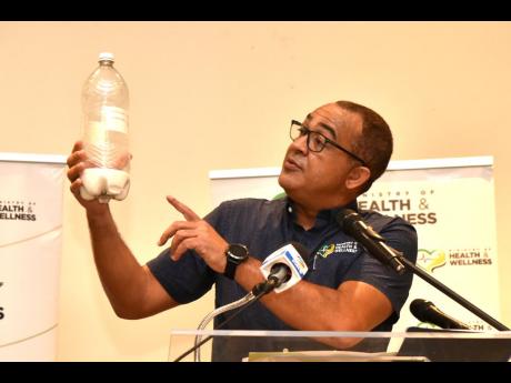Minister of Health Dr Christopher Tufton shows the amount of sugar in one two-litre beverage currently on the local market as he addressed a press conference on sugary drinks in schools and the many health issues they cause at The Jamaica Pegasus hotel in 