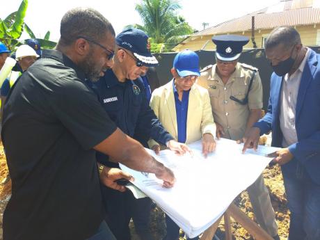 Errol Carty (left), project manager, examines building plans for the new $175-million Frome Police Station alongside Police Commissioner Major General Antony Anderson (second left), Dr Horace Chang (centre), minister of national security, Wayne Joseph (sec
