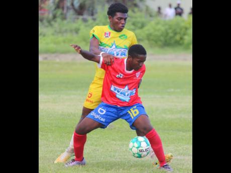Kemps Hill High’s Lamark Hope shields the ball from the pressing Vere Technical midfielder Kevon Lindo during yesterday’s ISSA/daCosta Cup match at Vere Technical.