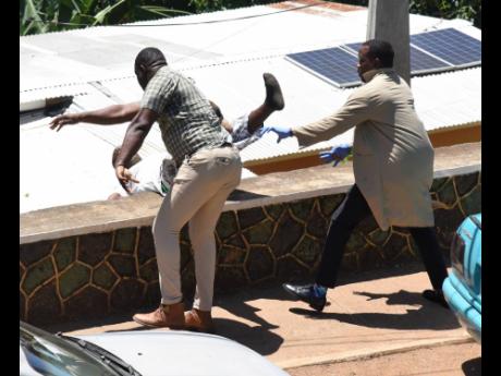 Garfield Winter, a resident of Walkers Hill in Red Hills, St Andrew, falls over a wall after allegedly being pushed by a cop from the St Andrew North Police Division. A member of the police’s forensic unit tried to prevent the man from falling. Winter wa