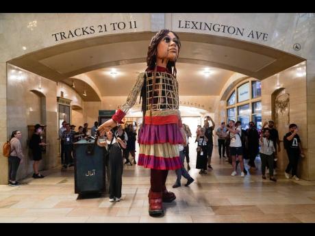 A large puppet named Little Amal walks around Grand Central Station in New York. The 12-foot puppet of a 10-year-old Syrian refugee, is on a 17-day blitz through every corner of the Big Apple as part of a theatre project hoping to raise awareness about imm