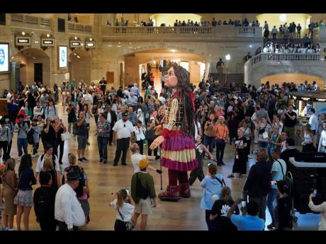 A large puppet named Little Amal walks around Grand Central Station in New York.