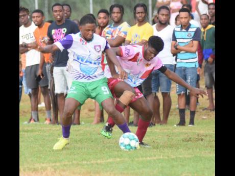 William Knibb Memorial High School’s Mark Lewis (left) battles for the ball with Spot Valley High’s Javane Clarke during an Inter-Secondary Schools’ Sports Association (ISSA)/Digicel daCosta Cup football match at William Knibb yesterday. The hosts wo