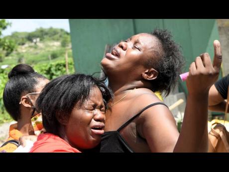 An unidentified family member comforting Sue-Ann Ebanks (right), sister of Sasha-Gaye Ebanks, who was shot and killed in Spring Village, Old Harbour, Sunday afternoon. 