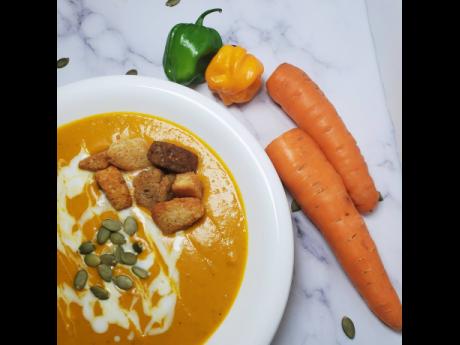 The carrot pumpkin cream soup is topped with croutons and pumpkin seeds.