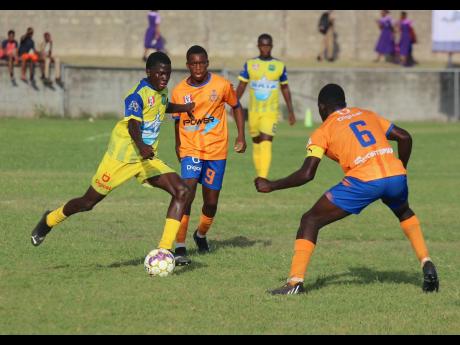 Clarendon College’s Keheim Dixon (left) on the move as he is flanked by Lennon High School’s Richardo Ramsay (centre) and Raymond Ford during their ISSA daCosta Cup Zone ‘H’ encounter at Foga Road High School yesterday.