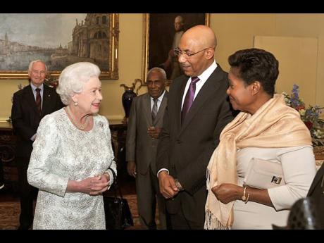 Queen Elizabeth II speaks with Sir Patrick Allen, the governor general of Jamaica, and his wife Lady Allen at Buckingham Palace during a visit to London in 2012.