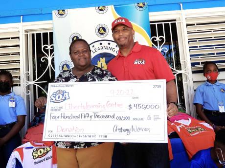Rosemarie Brent-Harris, principal of Liberty Learning Centre, accepts a cheque from Anthony Warren (right), CEO of Standard of Athletics, on Tuesday to assist with the building of a multipurpose court at the St Mary school. 