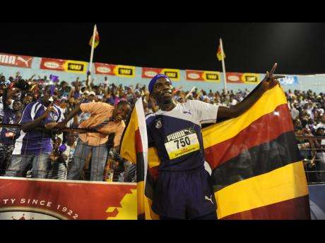 Kingston College athlete, Ugandan Ari Rodgers, poses with his national flag after winning the  5000 metres open at the 2017 ISSA/GraceKennedy Boys and Girls’ Championships.