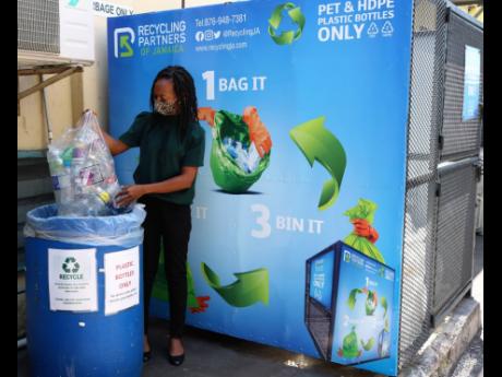 Quality Assurance Manager at Salada Foods Jamaica Limited, Nadine Frances, prepares to drop a bag of plastic bottles into one of the 55-gallon capacity recycling bins at the company’s Bell Road, Kingston 11 office. 