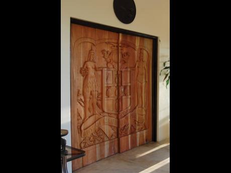 Magnificently carved front doors with the Jamaican coat of arms symbol.