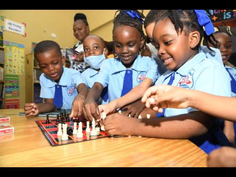 Students playing a game of chess in the newly opened Reading Owls International Library at the Jamaica China Goodwill Infant School on Olympic Way in St Andrew on Friday.