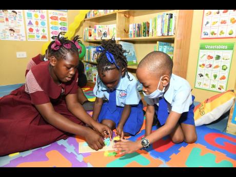 Students Ashamoy Dunston, Akelia Robinson and Kevron McLeod enjoy activities in the just-opened Reading Owls International Library at the Jamaica China Goodwill Infant School on Olympic Way in St Andrew on Friday.