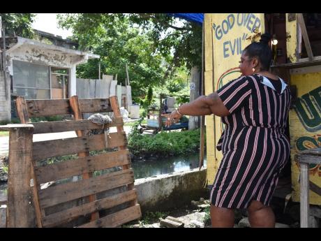 Along Railway Lane, 47-year-old businesswoman Lisa Campbell uses two pallets to prevent the garbage washed out of the drains from entering her shop when it rains.