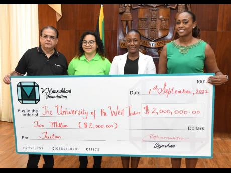 Juliet Holness (right), member of parliament for St Andrew East Rural, and Gul Mansukhani (left) of the V. Mansukhani Foundation, present a symbolic $2-million scholarship cheque to be shared by student nurse Zoe Hitchins (second left) and Gavieal Gordon d