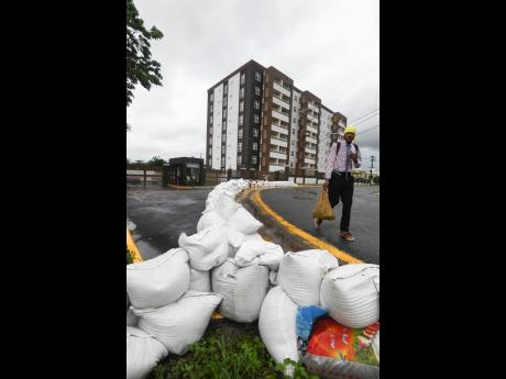 A man walks by sandbags placed at the entrance to Ruthven Towers in New Kingston to prevent flooding of the upscale apartment complex as Hurricane Ian dumped rain on Jamaica though it veered southwest of the island.