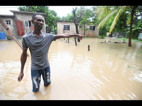 Derrick Lampard, a resident of 40 Job Lane, St Catherine, points to an overflowing drain that causes water to breach his yard.