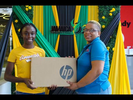 GK Foundation scholarship recipient Kimberlee Coley (left) receives a laptop from Marjorie Godfrey, administrative assistant at the GK Foundation on August 31 ahead of the new school year.
