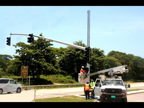 Workmen install the first set of traffic lights to be placed in the parish of Hanover, on Monday July 11, 2022.  The system is being installed at the entrance to the Oceanpointe Housing Development, at Point, in Eastern Hanover. 