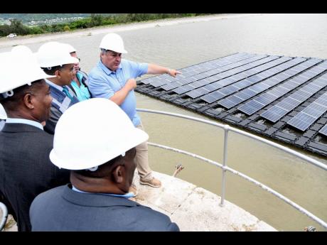 Simon Piggott (right), CEO of Derillion Energy Jamaica, explains the workings of the floating solar project to (from forefront) Michael Shaw, chairman of the National Water Commission (NWC); Mark Barnett, NWC president, and Prime Minister Andrew Holness du