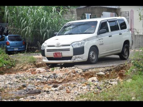 A taxi crawls along a road in Green Bottom, southeast Clarendon, which suffered devastating flood rains Monday. 