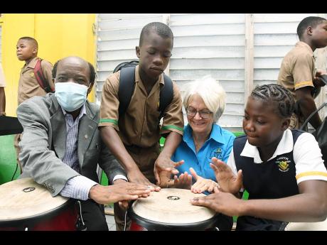 Kingston High School students Romario Nelson (second left) and Andrea Williams teach Professor Elizabeth Ward (second right), chair of the Violence Prevention Alliance, how to play the drum as Professor David Akombo, dean of the Faculty of Culture, Creativ