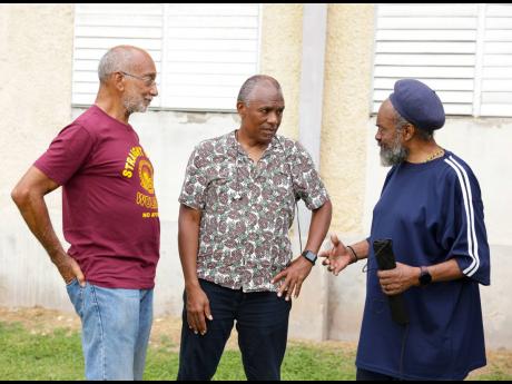 Douglas Orane (left), director - Wolmer’s Board of Trustees and Lennox Robinson (centre), CEO  E-Payment Group Limited, listen keenly as JC Old Boy Mickey Mowatt, recounts his memorable goal from the half line against Calabar in the 1963 Manning Cup comp