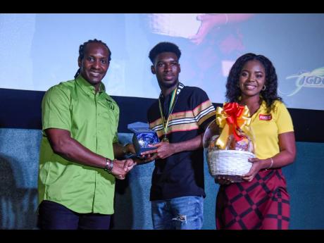 Alando Terrelonge (left), state minster, Ministry of Culture, Gender, Entertainment and Sport, makes a presentation to Keron Watson, creator of ‘Friend Killa’, which won the first-place prize in the youth section. At the right is Natovia Shand, marketi