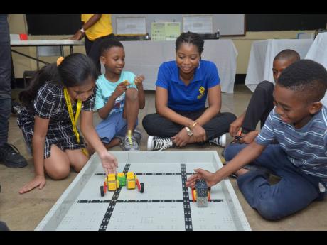 
At the Junior Creator Robotic Camp, Supreme Ventures Limited (SVL) Social and Digital Media Asst. Manager, Precianne Miller (middle), sits in with the excited students of Independence Primary School (from left to right): Katalina Baroo, Javaughn Dixon, an