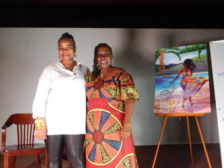 Christine Randle (left), managing director of Ian Randle Publishers, is happy standing beside author Opal Palmer Adisa. On the easel beside them is a picture of the book’s cover.