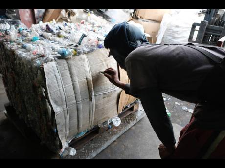 A worker records the weight of the bale of plastic bottles, which are being prepared for export at the Recycling Partners of Jamaica depot in Lakes Pen, St Catherine.