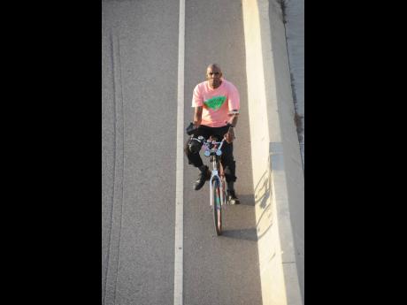 A man is seen riding a bicycle along Highway 2000 in this February 26, 2014, photograph. Two young lobbyists have called for bicycle lanes in Jamaica.