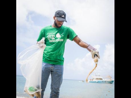 ESIROM volunteer and Norman Manley Law School Environmental Club member, Steven Harvey, empties the sand from a bottle that was embedded during the International Coastal Clean-up Day Little Bay Beach collaboration with ESIROM.