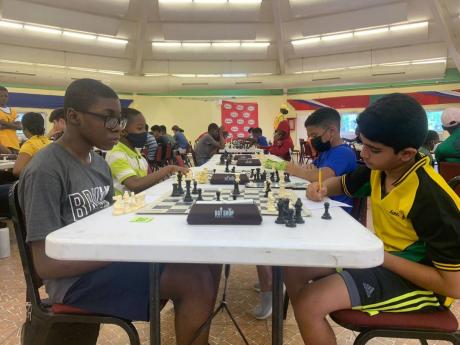 Under 12 Absolute champion Zahmir Smikle (left) looks on as Ronak Shergil records his moves during Round 3 of the National Age Group Chess Championships. 