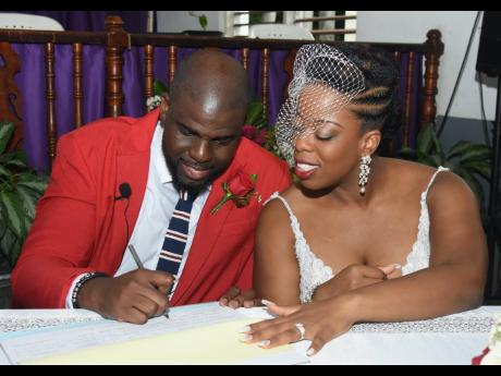 Dwayne Wilks signs his marriage licence and certificate as his wife Deon watches during their wedding ceremony at the Fletcher's Baptist Church on Saturday, September 24.