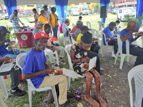 Homeless persons enjoy a meal on World Homeless Day at the old police station in May Pen on Monday.