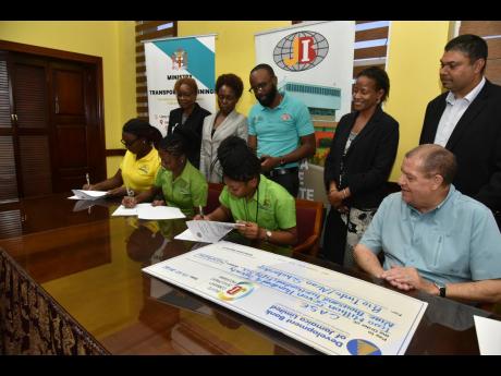 Students (seated, from left) Tamai McLean, Daunja Galloway, and Celine Sitladeen sign contracts after being awarded Rio Tinto Alcan Legacy Fund scholarships to attend the College of Agriculture, Science and Education (CASE) on Thursday. The signing process