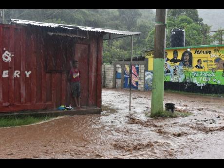 A child shelters as flood waters rage in Nine Miles in Bull Bay, St Thomas, resulting from Tropical Storm Ian, on September 25, 2022.