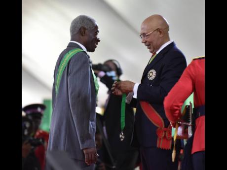 Governor General Sir Patrick Allen (right) inducts Professor Alvin Wint into the Order of Jamaica for his contribution to the development of public and private institutions and academia in Jamaica.