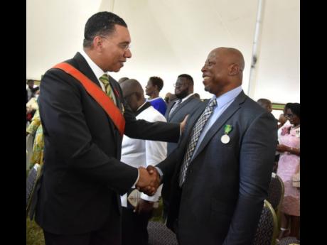 Prime Minister Andrew Holness (left) congratulates Gleaner photojournalist Rudolph Brown on being awarded the Badge of Honour for Meritorious Service for his contribution to journalism.