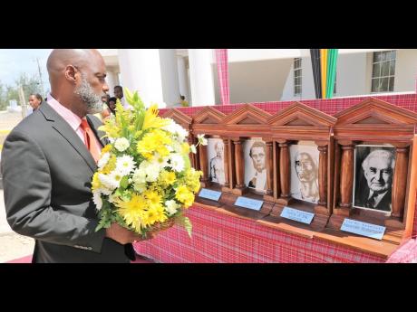 A solemn-looking Councillor Claude Hamilton prepares to pay tribute to Nanny of the Maroons with a floral arrangement during Monday’s Portmore Heritage, Civic and Awards ceremony.
