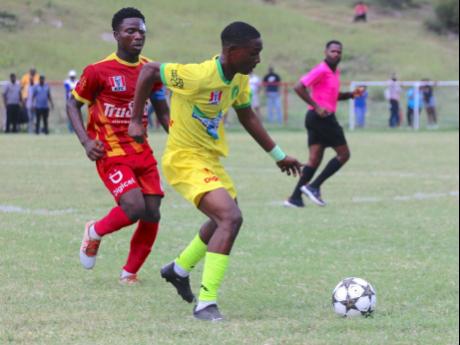 Vere Technical's Malcolm Lennon (right) dribbles away from Cornwall College's Giovanne Bruce during their ISSA daCosta Cup game at Glenmuir High School today.