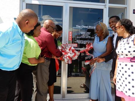 Custos Norma Walters and MP Marsha Smith (third and fourth left) join Audrey Stewart-Hinchcliffe (third right) in cutting the ribbon to officially open the Clean Store in Drax Hall. Others in photo are, from left: Kevin Davis and Sherona Findlay, of MMS; C