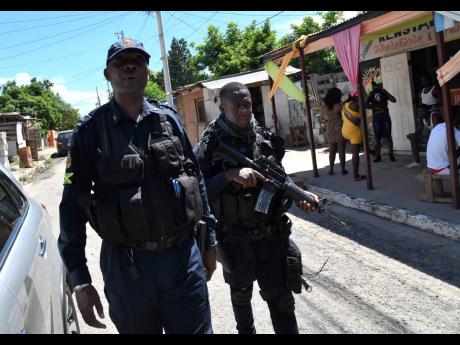 Policemen patrol Third Street in Trench Town where Corporal Oliver Mullings was killed in an alleged shoot-out in the Kingston Western Police Division last Thursday night.