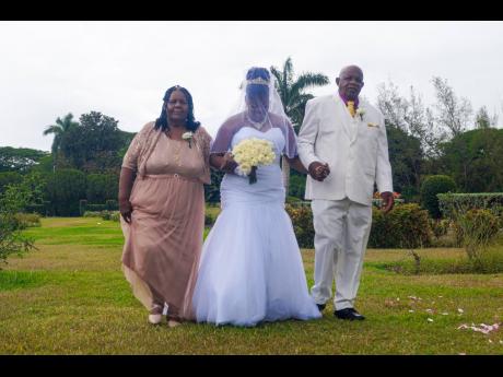Eva Francis-Williams and her husband, David Williams, parents of the bride, walk their last born (and last to wed) of 11 children down the aisle.