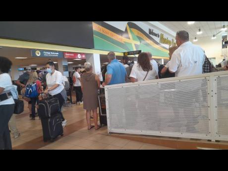 Passengers wait to be processed by immigration officers at the Sangster International Airport in Montego Bay, St James, on Wednesday, where several immigration officers called in sick.