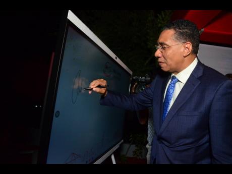A guest at  the event, Prime Minister Andrew Holness signs his signature on the Ideahub.