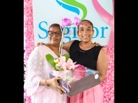 Two-time breast cancer survivor Gloria Thomas (left) receives a special blooming orchid, along with other gift items, from Karen Ramsay, a brand experience officer at Sagicor Group Jamaica.