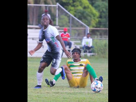 Cavalier’s goal scorer Dwyane Atkinson (left) leaves Vere United’s midfielder Javier Brown on his buttocks, during their Jamaica Premier League (JPL) encounter at the Wembley Centre of Excellence today. Cavalier won 3-0.